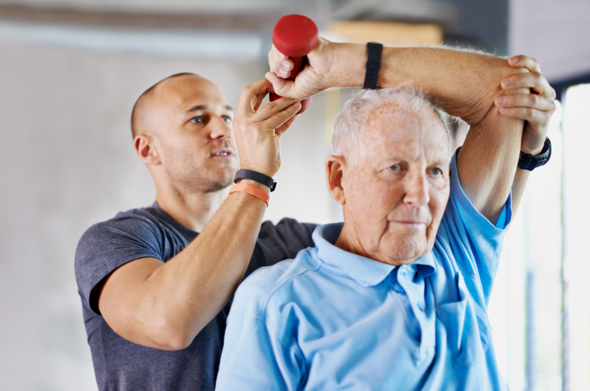 trainer helping guide exercise for elderly man