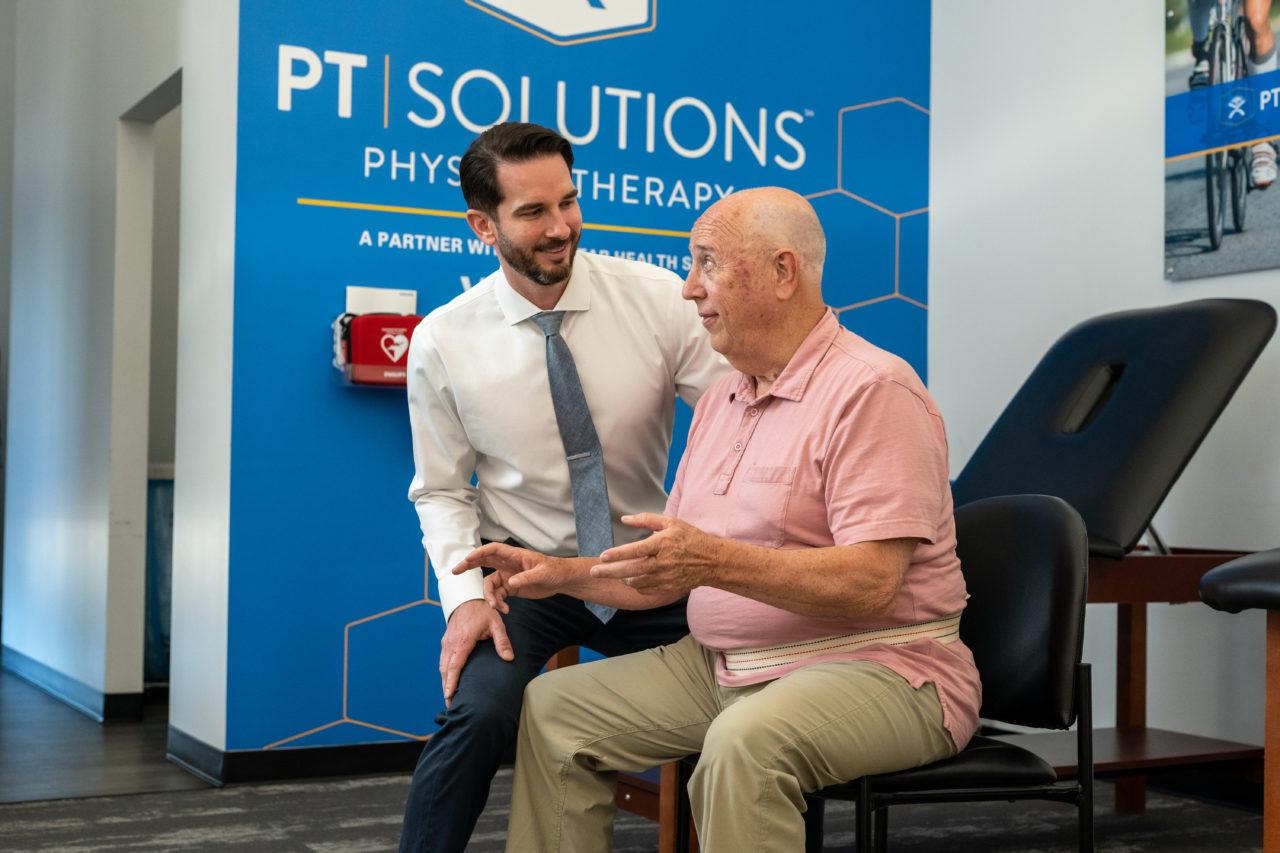 An Elderly Gentleman Receiving Therapy From a Smiling Man